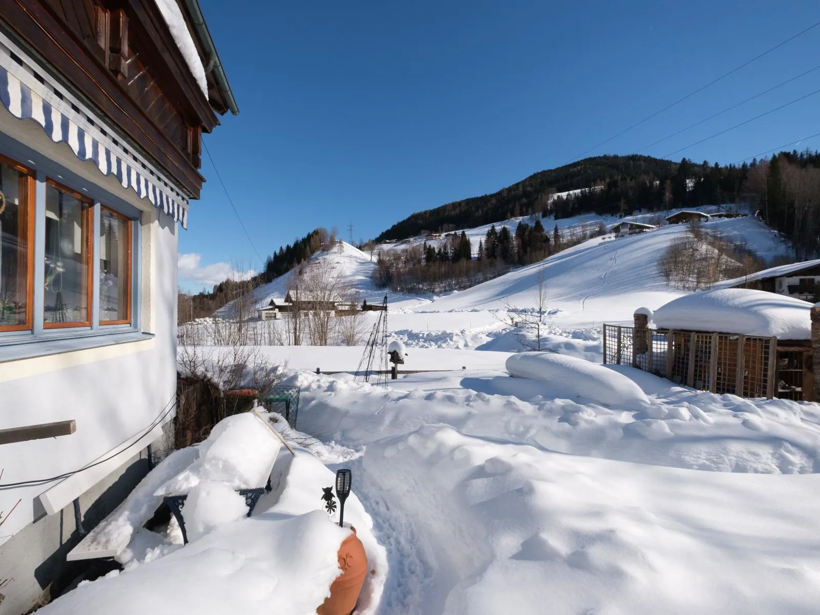 De besneeuwde tuinkant van het huis, met de velden erachter